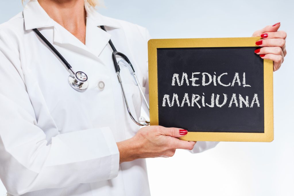 doctor holding a chalkboard with medical marijuana written on it